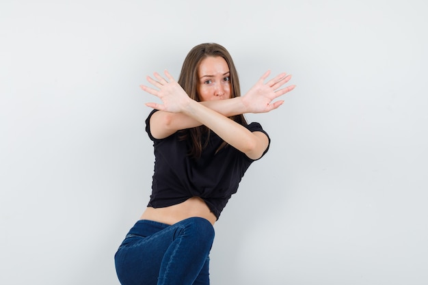 Bezpłatne zdjęcie młoda kobieta w czarnej bluzce pokazuje pięści, klęcząc i patrząc na gotowego