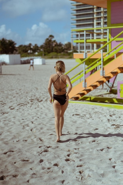 Młoda kobieta w czarnym stroju kąpielowym na plaży Miami Florida USA w pobliżu wieży ratownika.