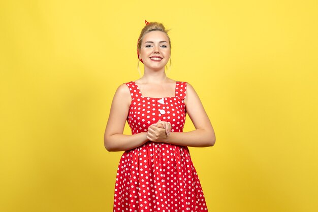 młoda kobieta w czerwonej sukience w kropki pozowanie na żółto