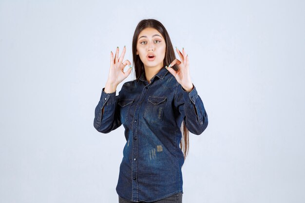 Młoda kobieta w dżinsowej koszuli pokazano pozytywny znak ręki