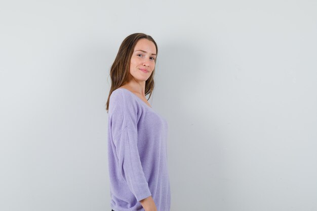 Młoda kobieta w liliowej bluzce, patrząc na bok i pewna siebie