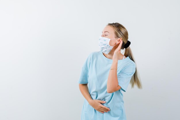 Młoda kobieta w niebieskiej koszulce z maską medyczną