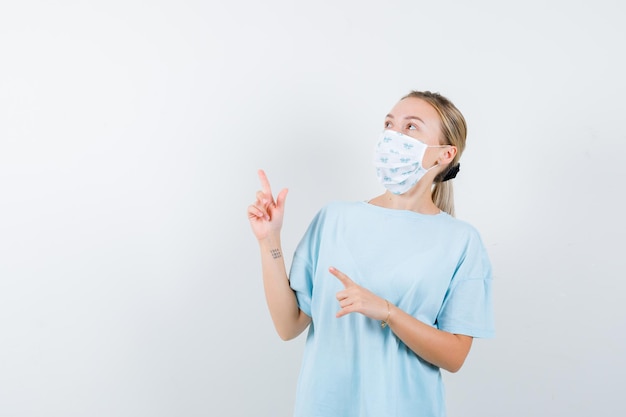 Młoda kobieta w niebieskiej koszulce z maską medyczną