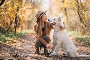 Bezpłatne zdjęcie młoda kobieta w parku z jej białym psem