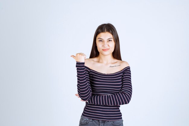 Młoda kobieta w pasiastej koszuli, wskazując na coś z tyłu
