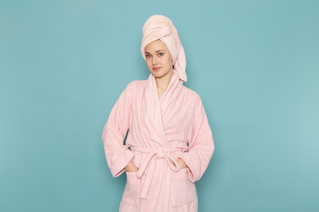 młoda kobieta w różowym szlafroku po prysznicu tylko pozuje na niebiesko