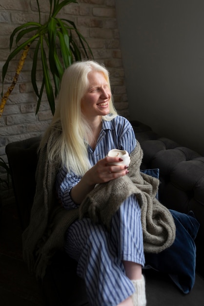 Bezpłatne zdjęcie młoda kobieta z albinizmem relaksuje w domu z przekąską