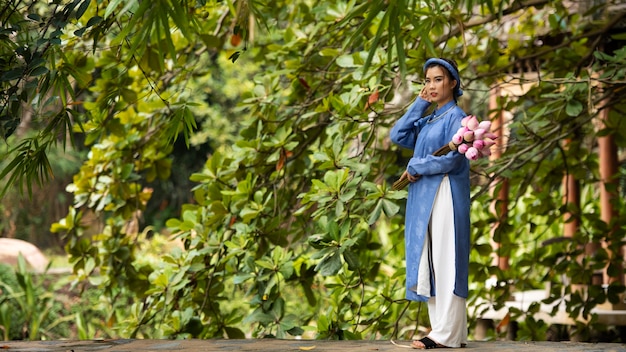 Bezpłatne zdjęcie młoda kobieta z bukietem kwiatów ubrana w kostium ao dai