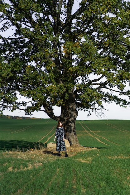 Bezpłatne zdjęcie młoda kobieta z długimi rudymi włosami w lnianej sukience w naturalnej lokalizacji