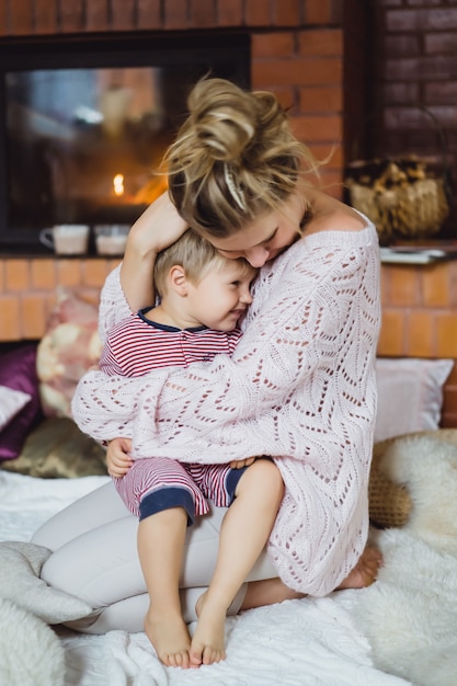 Bezpłatne zdjęcie młoda kobieta z dzieckiem. mama i syn żartują, bawią się przy kominku.