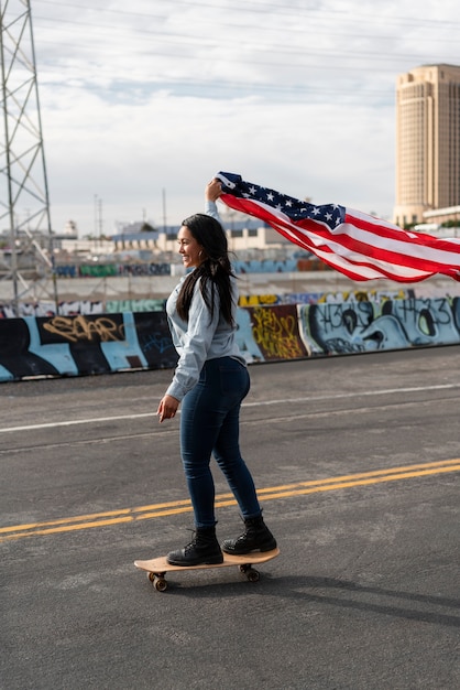 Młoda kobieta z flagą usa na deskorolce