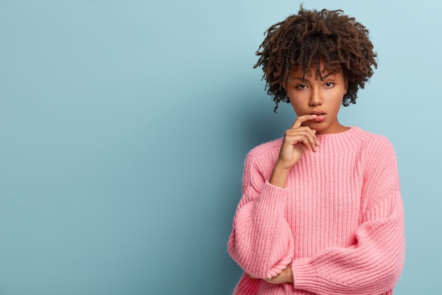 Młoda kobieta z fryzurą Afro na sobie różowy sweter