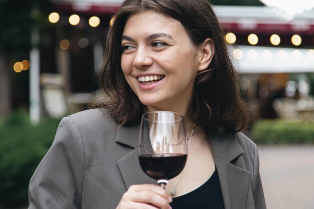 Młoda kobieta z kieliszkiem wina na zewnątrz w pobliżu restauracji