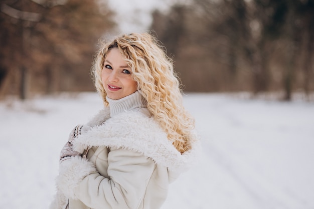 Młoda kobieta z kręconymi włosami spaceru w winter park