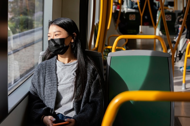 Bezpłatne zdjęcie młoda kobieta z maską w autobusie