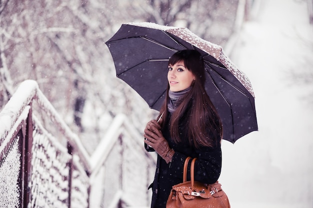 Młoda kobieta z parasolem w śniegu, retro stonowany obraz