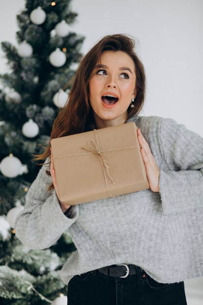 Młoda kobieta z prezentami świątecznymi przez choinkę