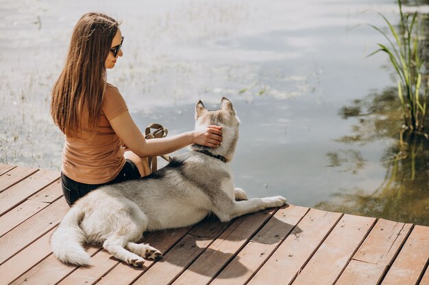 Młoda kobieta z psem husky nad jeziorem