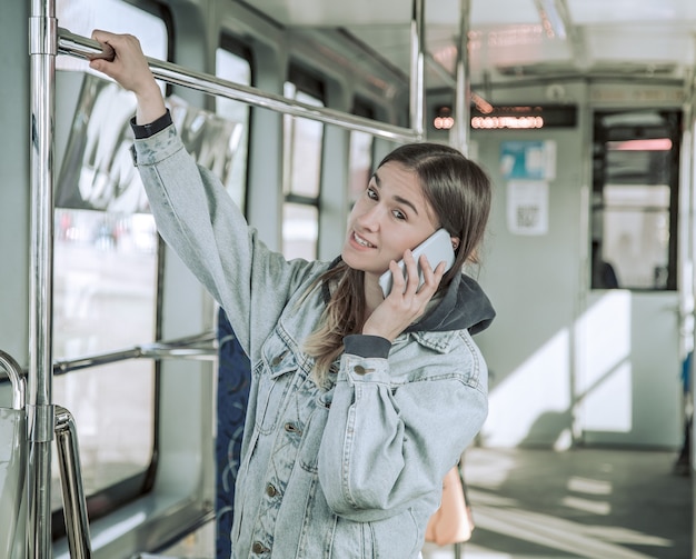 Młoda kobieta z telefonem w transporcie publicznym.