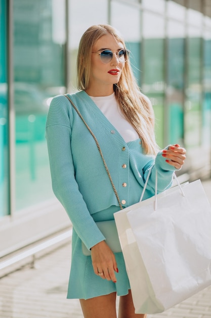 Młoda kobieta z torbami na zakupy przy centrum handlowym