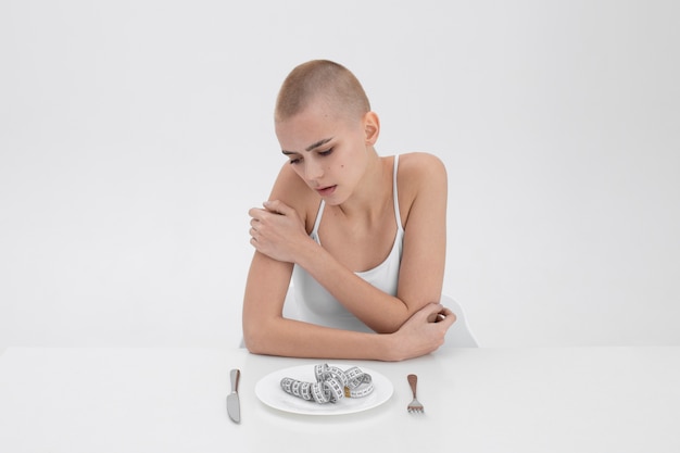 Młoda kobieta z zaburzeniami odżywiania mająca taśmę mierniczą na talerzu