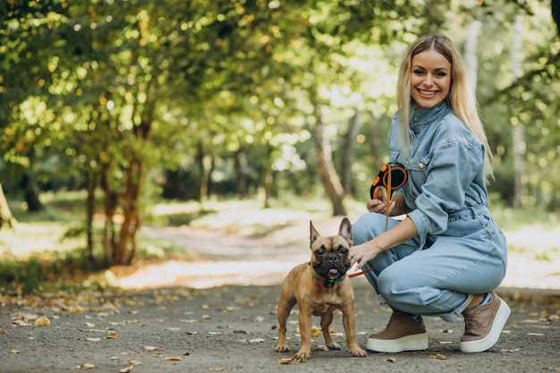 Młoda kobieta ze swoim zwierzakiem buldogiem francuskim w parku