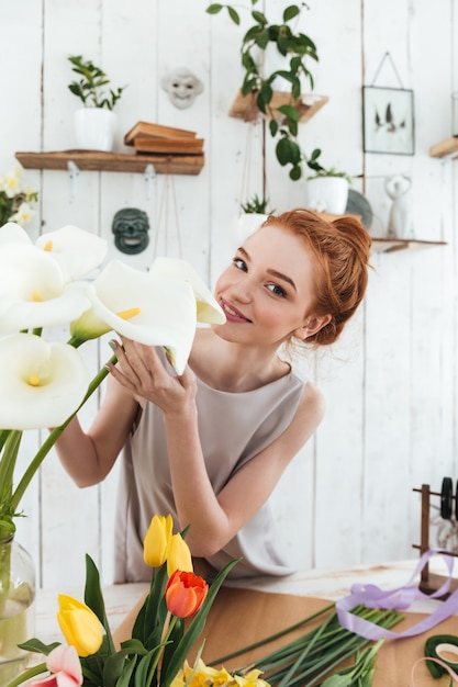 Bezpłatne zdjęcie młoda kwiaciarnia wącha białe kwiaty podczas pracy