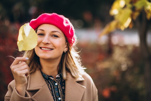 Młoda ładna dama w czerwonej barret na zewnątrz w parku