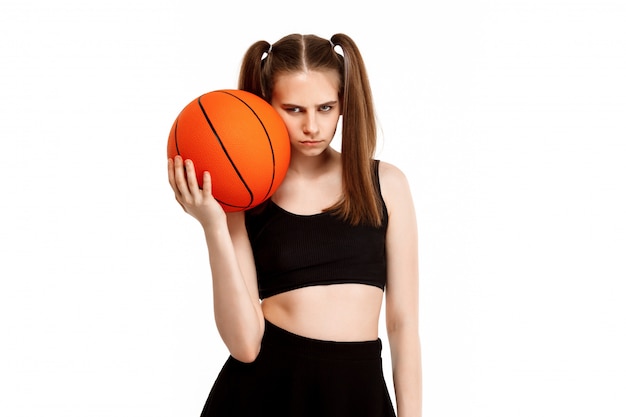 Bezpłatne zdjęcie młoda ładna dziewczyna pozuje z koszykówką, odizolowywającą na biel ścianie