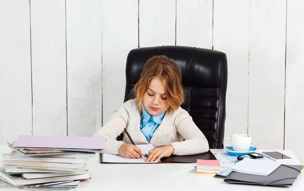 Młoda ładna dziewczyna siedzi w miejscu pracy, pisania w biurze.