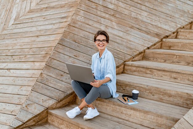 Młoda ładna kobieta pracuje na laptopie w nowoczesnej ulicy parkowej