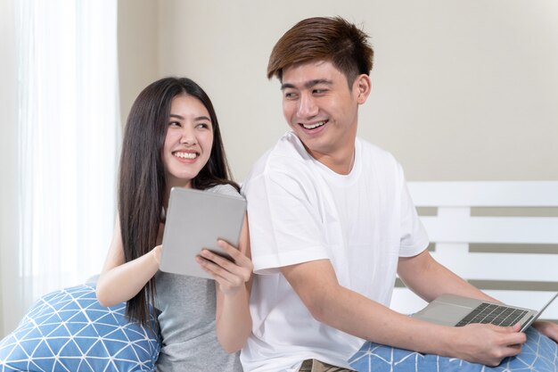 Młoda ładna kobieta za pomocą smartfona na czacie, a przystojny mężczyzna korzysta z laptopa z radosny