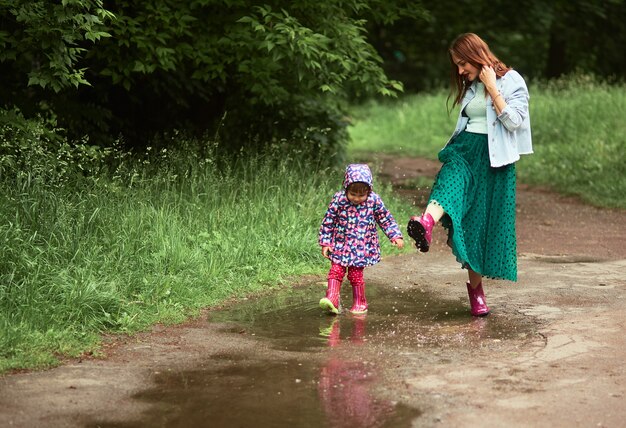 Młoda mama i mała córka bawią się spacery w gumboots na baseny w parku