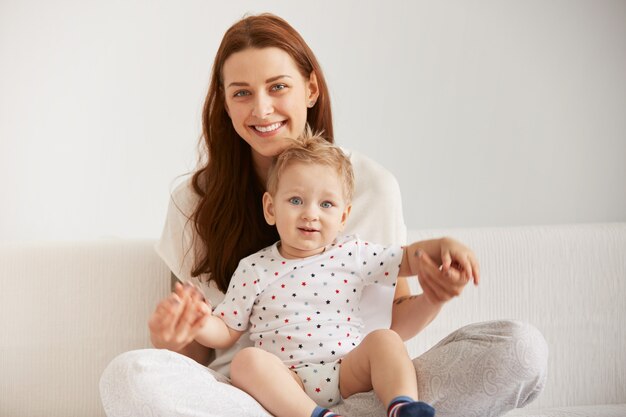 Młoda mama z rocznym synkiem ubrana w piżamę odpoczywa