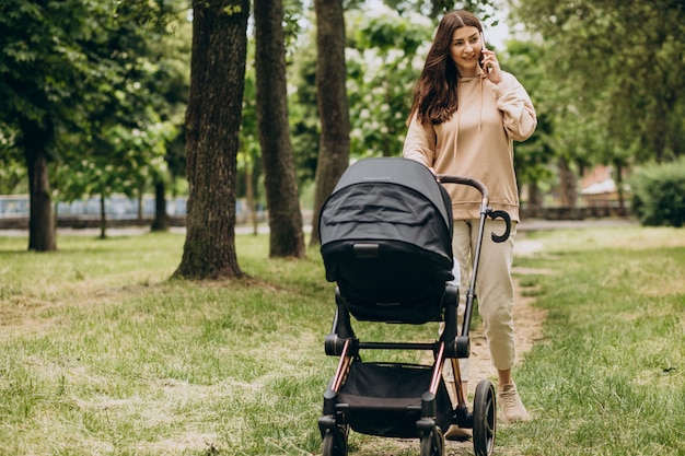 Młoda matka spaceru z wózkiem dziecięcym w parku