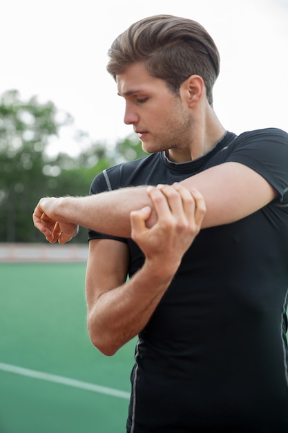 Młoda męska atleta robi rozciągającym ćwiczeniom outdoors