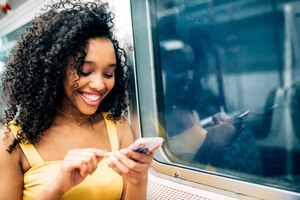 Młoda murzynka siedzi wewnątrz metra na telefonie komórkowym