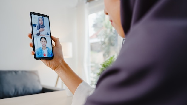 Młoda muzułmańska bizneswoman z Azji za pomocą smartfona rozmawia z kolegą przez wideoczat
