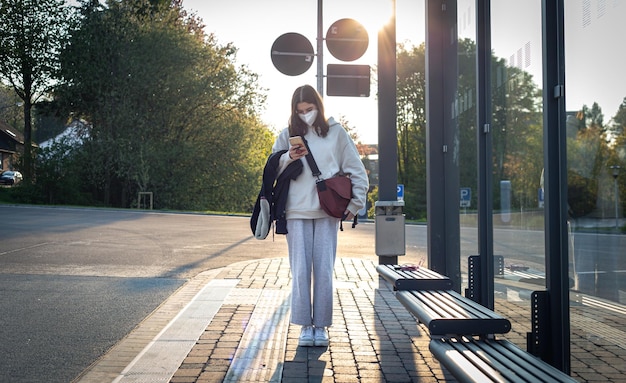 Bezpłatne zdjęcie młoda nastolatka czeka na autobus na przystanku wczesnym rankiem