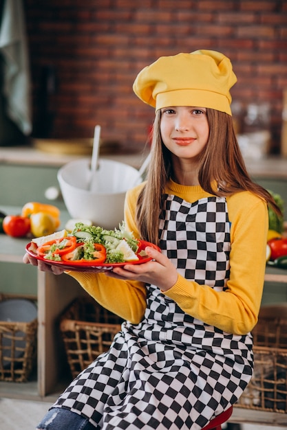 Bezpłatne zdjęcie młoda nastoletnia dziewczyny narządzania sałatka dla śniadania przy kuchnią