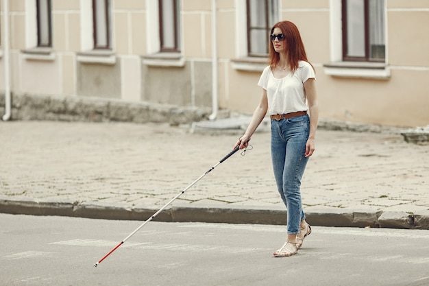 Młoda osoba niewidoma z długą laską spaceru po mieście