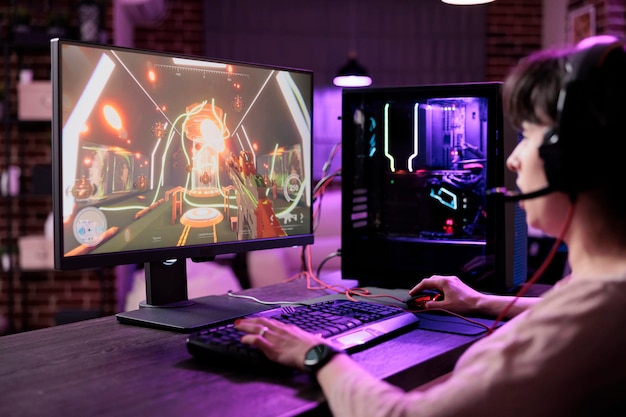 Młoda osoba przesyła strumieniowo mistrzostwa gier wideo na żywo na monitorze komputera, grając w gry online. Kobieta gracz bawi się z rozgrywką turniejową rpg akcji na komputerze dla rozrywki.