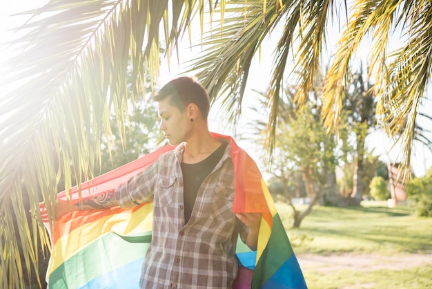 Bezpłatne zdjęcie młoda osoba stoi z flaga lgbt w parku