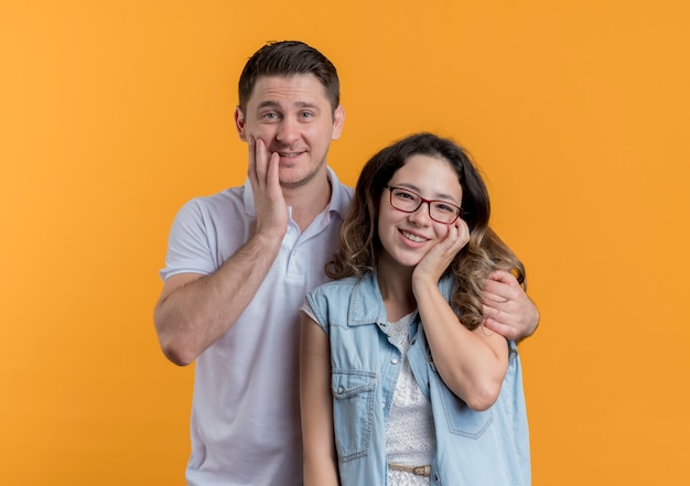 Młoda para mężczyzna i kobieta w ubranie szczęśliwy i pozytywny uśmiechnięty na pomarańczowo