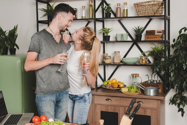 Bezpłatne zdjęcie młoda para patrząc na siebie trzyma szampana flet w kuchni