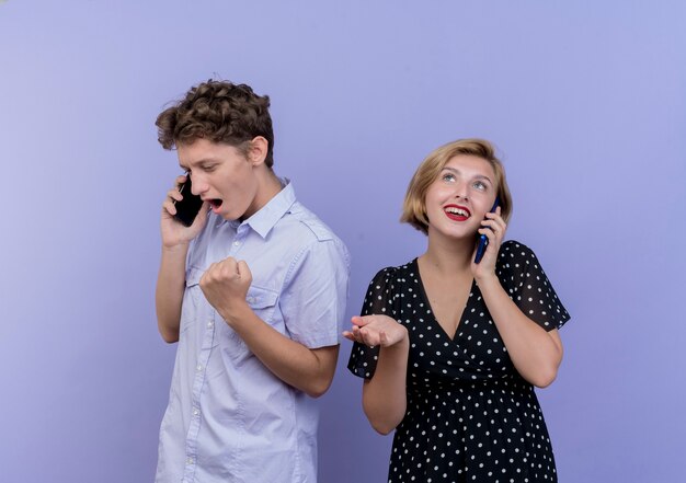 Młoda para piękny mężczyzna i kobieta rozmawia przez telefony komórkowe szczęśliwy i podekscytowany zaciskając pięści na niebiesko