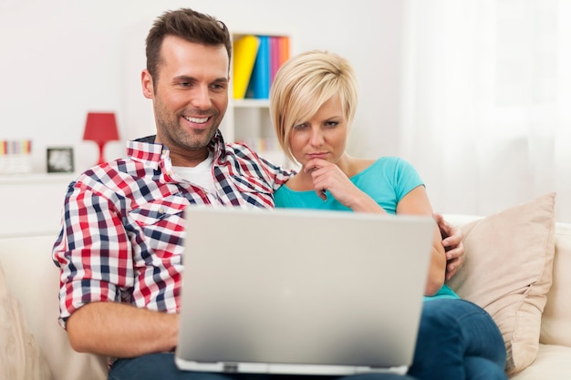 Bezpłatne zdjęcie młoda para siedzi na kanapie i korzysta z laptopa w domu