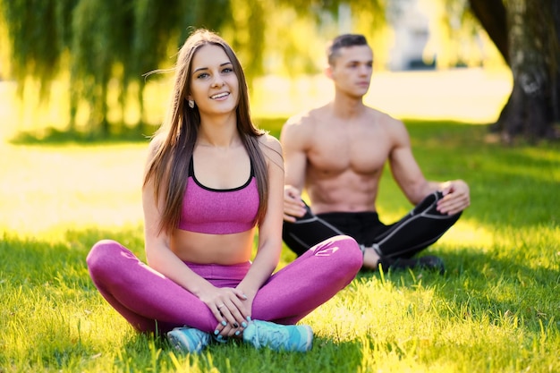 Młoda para sportowy relaks na trawie w parku po ćwiczeniach fitness i jogi.