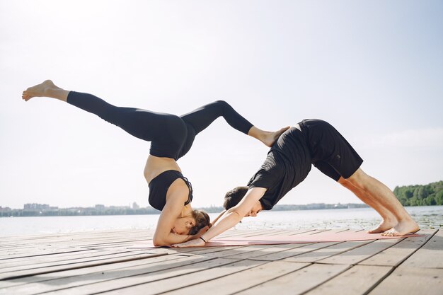 Młoda para sprawny robi joga fitness. Ludzie nad wodą.