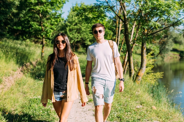 Młoda para w okulary przeciwsłoneczne chodzenia w pobliżu jeziora